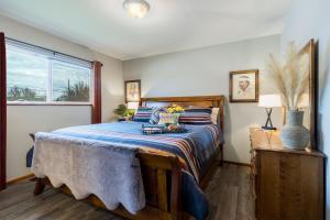 a bedroom with a bed with a blue comforter and a window at Pendleton House - Complimentary Wine Tasting in Walla Walla