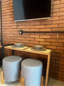 una mesa con dos taburetes y una TV en una pared de ladrillo en Casa do Coité en Río de Janeiro