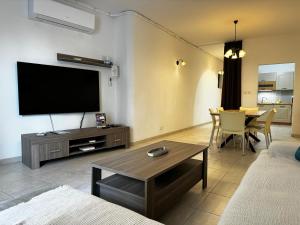 ein Wohnzimmer mit einem Flachbild-TV und einem Tisch in der Unterkunft Holiday Home in St. Paul’s Bay in St Paul's Bay