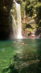 two people swimming in the water in front of a waterfall at Casa Bosque da Saudade in Barra do Garças