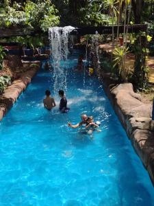 a group of people in a swimming pool with a waterfall at Casa Bosque da Saudade in Barra do Garças