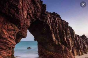 an arch in a rock wall next to the beach at kitnet Cidade 2000 in Fortaleza