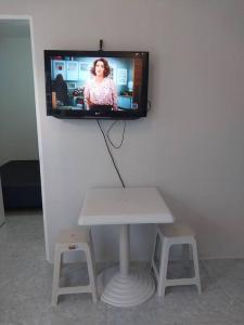 a tv on a wall with a table and stool at kitnet Cidade 2000 in Fortaleza