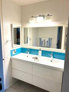 a bathroom with two sinks and two mirrors at Beachside Retreat in Oceanside