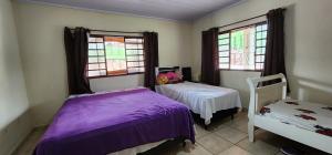 um quarto com 2 camas e 2 janelas em Fazenda Araras Eco Turismo - Acesso a cachoeira Araras em Pirenópolis