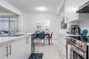 a kitchen with white cabinets and a dining room with a table at Spacious 5-Bedroom Home with 4.5 Bathrooms: 3 Sassafras Road in Midhurst