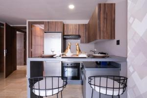 a kitchen with a counter with three chairs in it at Luxoria by SHORTSTAYCASA- New & Chic in the heart of town in Casablanca