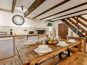 a kitchen with a wooden table and a clock on the wall at 3 Bed in Lanhydrock 90214 in Bodmin