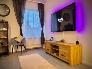a living room with a tv on a wall with purple lights at G&G Luxury Apartment am Stadtpark Bendorf in Bendorf