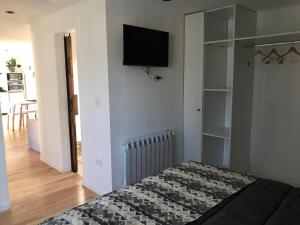 a bedroom with a bed and a tv on the wall at Complejo Del Este Suites in San Carlos de Bariloche