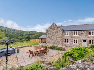 a stone barn with a table and chairs in a garden at 3 Bed in Gwynfryn 83938 in Coedpoeth