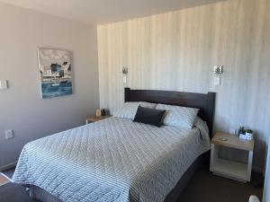 1 dormitorio con 1 cama con edredón blanco y negro en MoanaViews, en Nelson