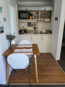 uma pequena cozinha com uma mesa de madeira e cadeiras brancas em MoanaViews em Nelson