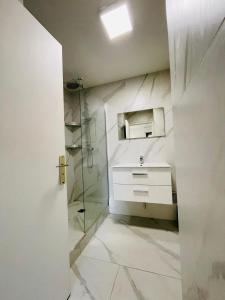 W łazience znajduje się umywalka i przeszklony prysznic. w obiekcie Appart Neuilly bagatelle Porte Maillot 4 Pers w mieście Neuilly-sur-Seine