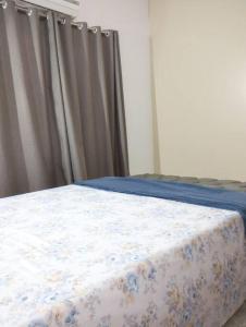 um quarto com uma cama com um cobertor azul e branco em Casa aconchegante em Cascavel