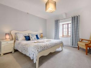 a bedroom with a bed and a chair and a window at 4 Bed in Bude 85839 in Morwenstow