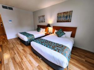 duas camas num quarto de hotel com pisos de madeira em Sunset Mountain Inn em Canmore