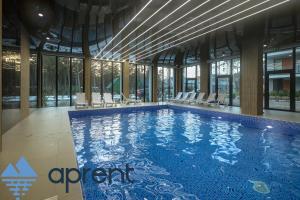 a large swimming pool in a building with windows at Apartament AURI Pobierowo Baltic Apartments - Aprent in Pobierowo