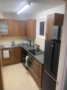 eine Küche mit Holzschränken und einem schwarzen Kühlschrank in der Unterkunft Cozy flat in Birmingham with Parking in Birmingham