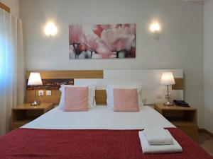 a bedroom with a white bed with pink pillows at Hotel SQUARE in Sertã
