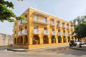 a yellow building with white balconies on a street at Hermoso apartamento en la Ciudad Amurallada Cartagena de Indias in Cartagena de Indias