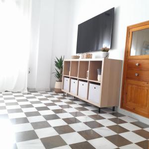 uma sala de estar com televisão e piso em xadrez em Casa Cervantes em Granada
