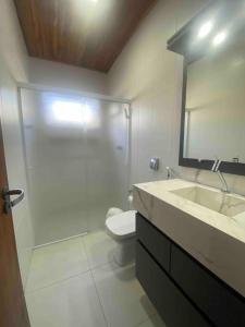a bathroom with a toilet and a sink and a mirror at Casa de praia aconchegante in Barra Velha