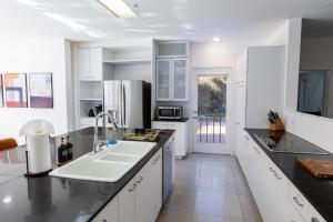 a kitchen with white cabinets and a white sink at Elite Retreat! Hot Tub, Arcade, & Theater. 6 Beds! in Encinitas