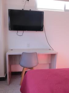 a desk with a television on a wall with a chair at Hotel Urban Cholula in Cholula