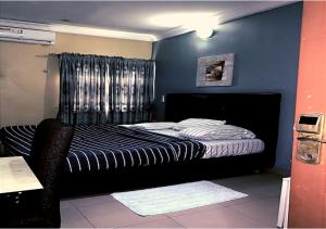 een slaapkamer met een bed met een blauwe muur bij angelaMcFadden apartment in Benin City