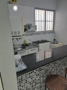 a kitchen with white appliances and a black counter top at Aconchegante Apto de 1qt a 60mts do Consulado EUA in Recife