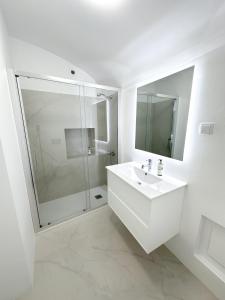 uma casa de banho branca com um lavatório e um chuveiro em Largo Inn Suites Evora em Évora