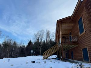 a log cabin in the snow with a wooden staircase at Mountain Views! Copper Cannon Lodge in Franconia in Franconia