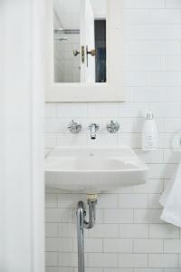 a white bathroom with a sink and a mirror at The Nunnery and Spa in Leura