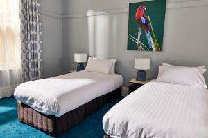 a room with two beds and a bird painting on the wall at The Nunnery and Spa in Leura