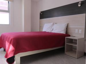 een slaapkamer met een rood bed en een houten hoofdeinde bij Hotel Urban Cholula in Cholula