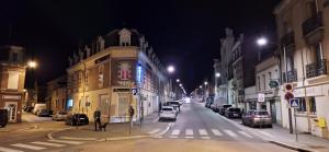 una strada di città di notte con auto parcheggiate di Hôtel Le Saint Quentin a Saint-Quentin