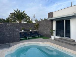a swimming pool with chairs next to a stone wall at Villa Grey in Tahiche