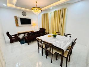 une salle à manger avec une table, des chaises et une télévision dans l'établissement MHI Homestay Bandar Baru Jelawat, à Bachok