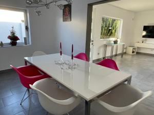 a dining room with a white table and red chairs at Villa Grey in Tahiche