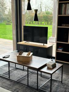 a coffee table in a living room with a tv at Villa en bois à la campagne - 20 min de Rouen in Morgny-la-Pommeraye