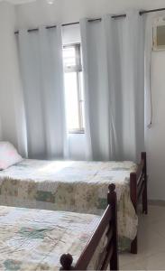 Un dormitorio con dos camas y una ventana. en Apartamento pé na Areia de Frente para o Mar, en Arraial do Cabo