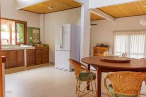 uma cozinha com uma mesa e um frigorífico branco em Alter do Chão, suite master+2 dormitórios c/A.C. paz e natureza a 100m da praia do Lago Verde e 500m da Ilha do Amor em Alter do Chão