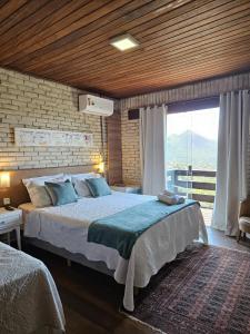 a bedroom with a large bed and a large window at Pousada Vale das Flores in Nova Friburgo