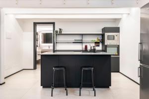 una cocina con una isla negra y dos taburetes en Diaz Novantuno - Luxury Apartments Como City Center, en Como