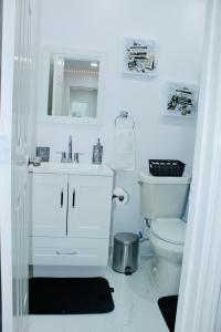 a white bathroom with a toilet and a sink at Luxury Studio only 5 miles to IAH in Humble