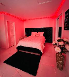 um quarto rosa com uma cama e um vaso de flores em Luxury Studio only 5 miles to IAH em Humble
