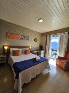a bedroom with a large bed and a chair at Pousada Vale das Flores in Nova Friburgo