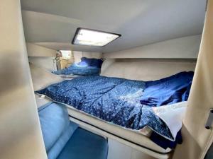 uma cama na parte de trás de uma caravana com lençóis azuis em Superbe bateau à Gruissan em Gruissan