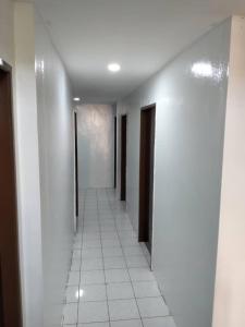 a hallway with white walls and a white tile floor at Hotel Iramanis in Lahad Datu